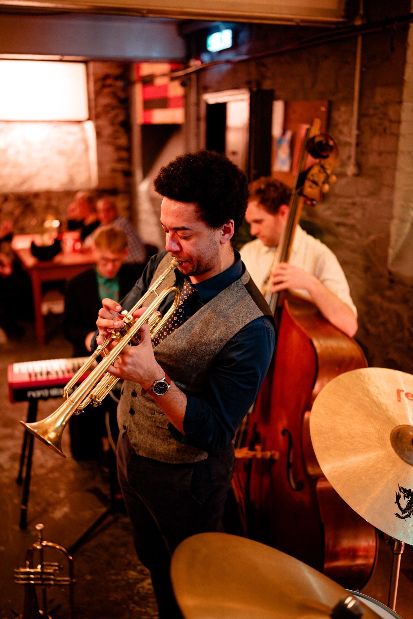 Trumpet player performing at an intimate jazz venue with double bass player behind